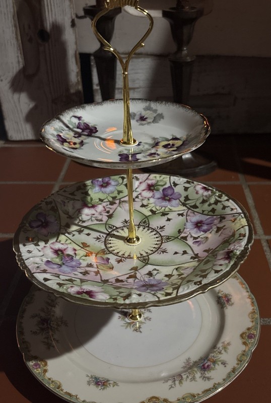 A three-tier porcelain cake stand with mismatched floral plates and gold trim.